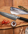 kotai pakka damascus koksmes gyuto 20 cm pakkahout op houten snijplank met vis en tomaat